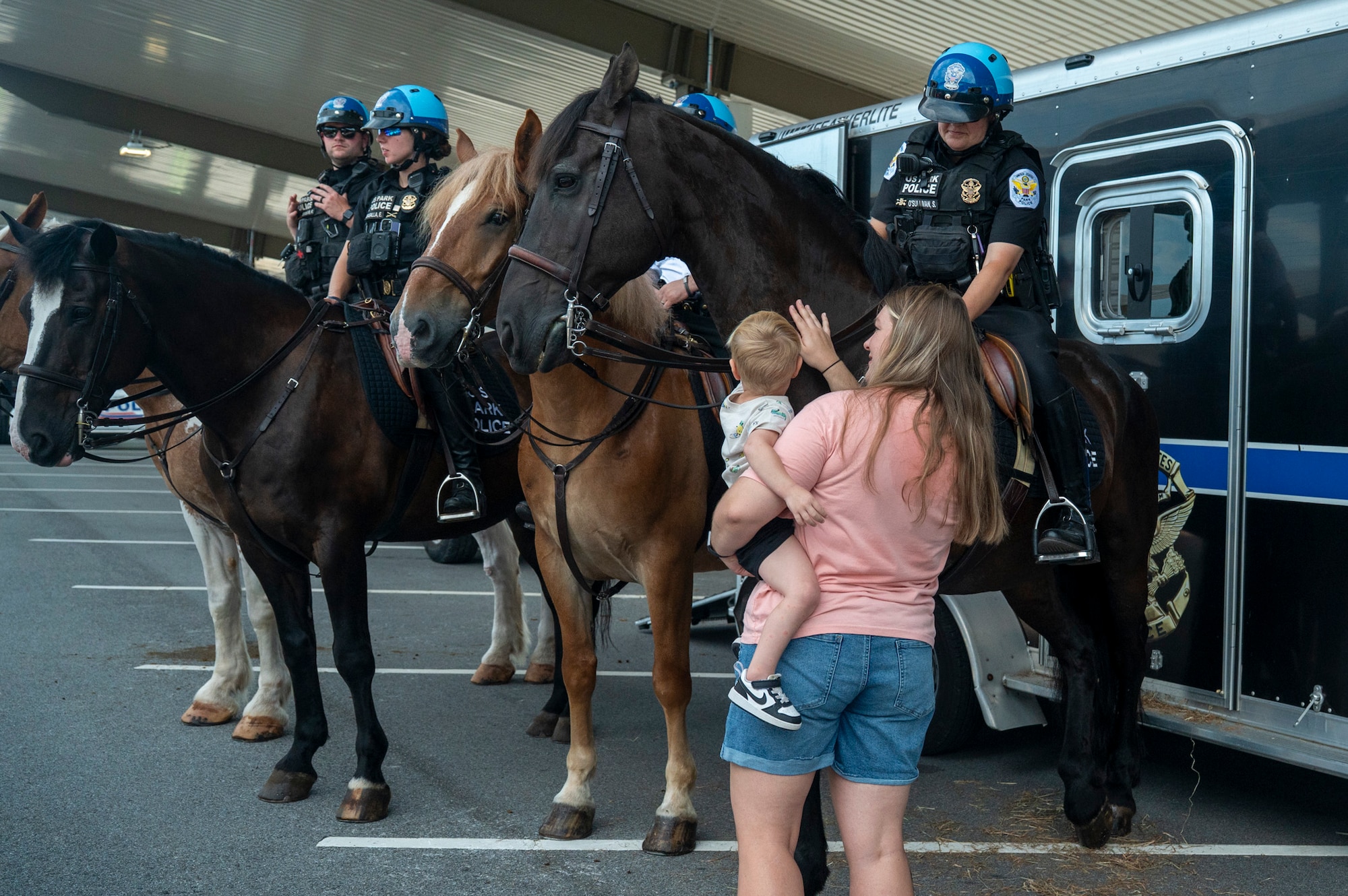 A mother and child pet a U.S. Park Police mounted patrol horse