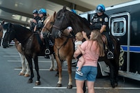 A mother and child pet a U.S. Park Police mounted patrol horse