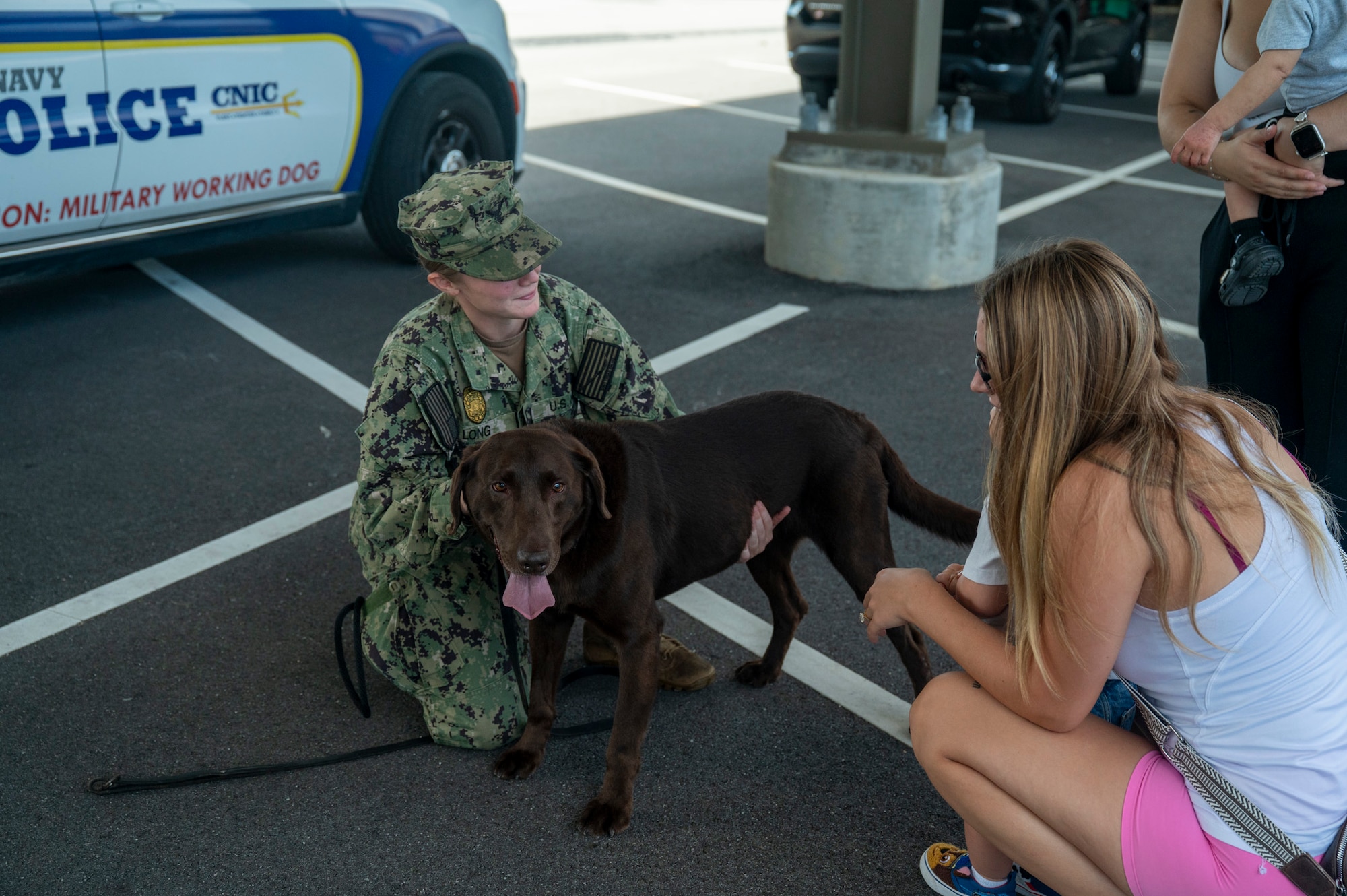 U.S. Navy Master-at-Arms 3rd class introduces her military working dog to a mother and her son.