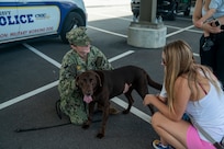 U.S. Navy Master-at-Arms 3rd class introduces her military working dog to a mother and her son.