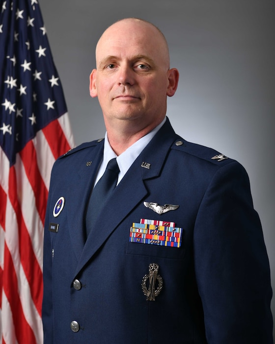 Man in military uniform in front of a flag