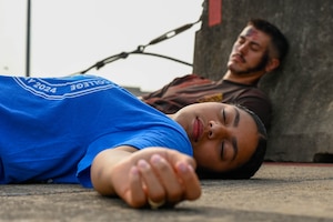 Two people lay on the ground roleplaying casualties.