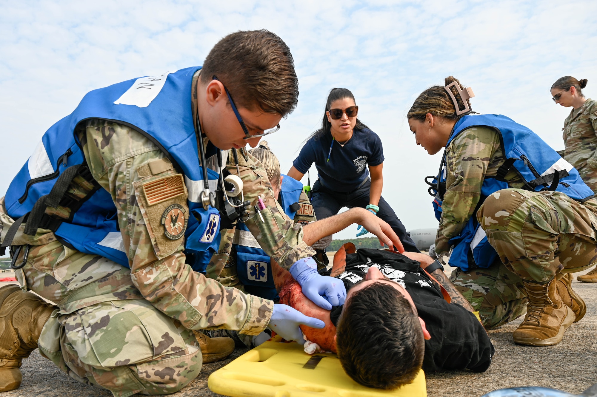 Airmen place a person on a litter.