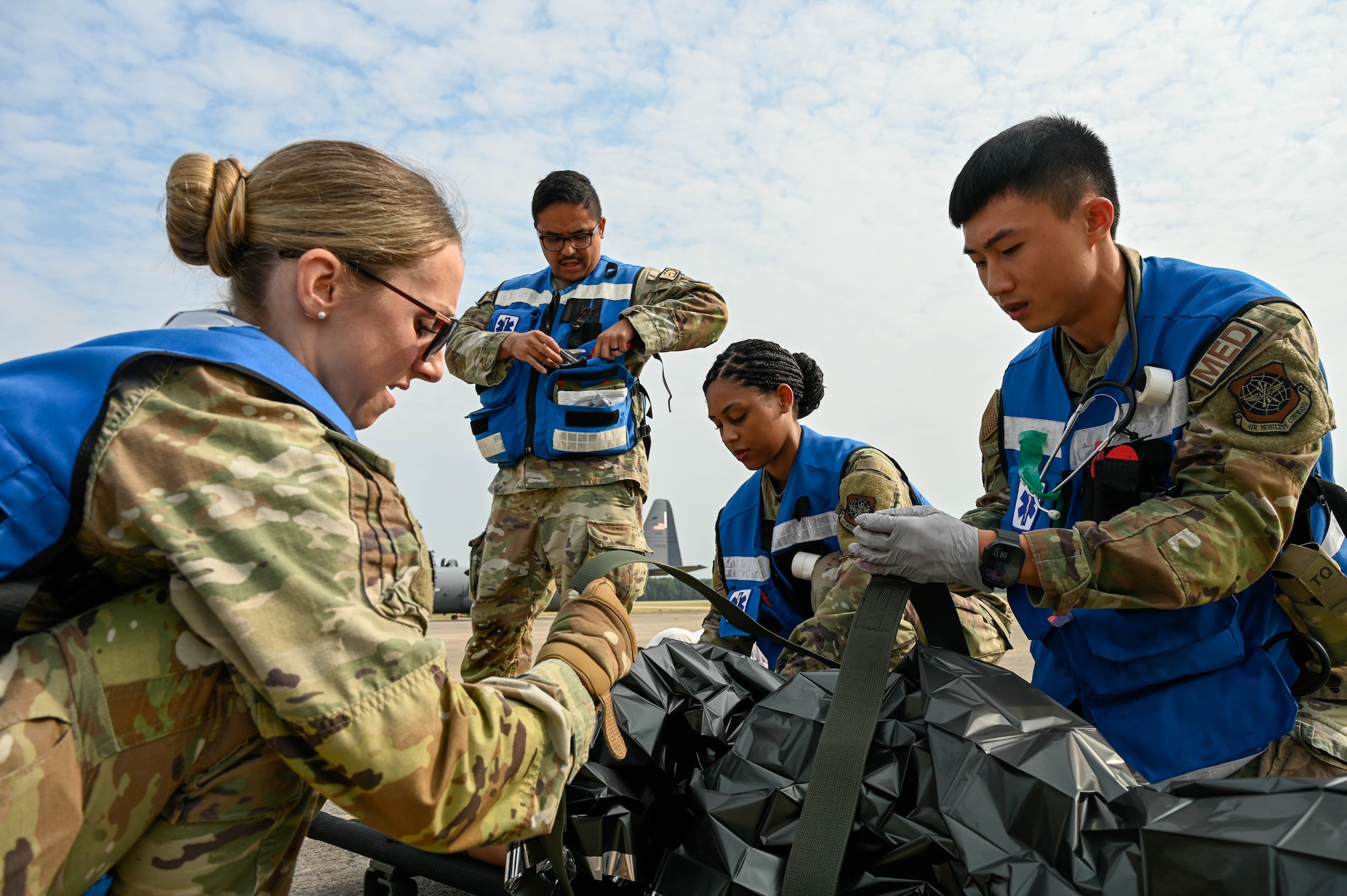 Airmen secure a person to a litter.