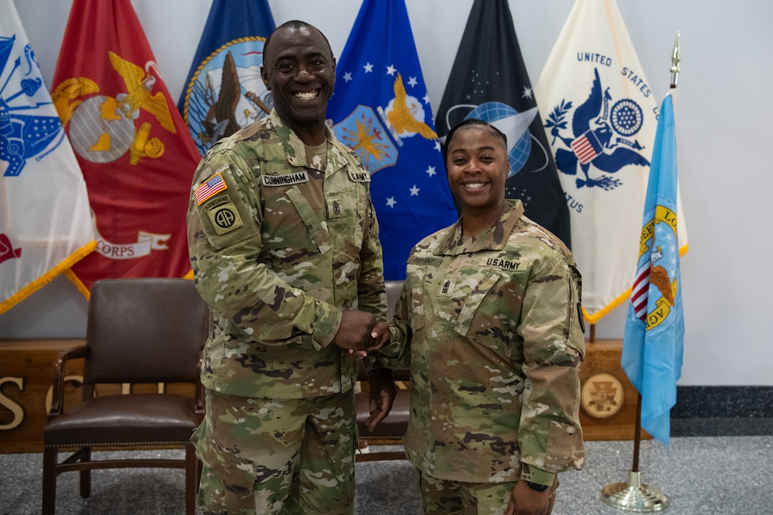 two people wearing camouflage military uniforms shake hands