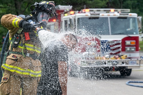 Image of firefighter spraying water on person.