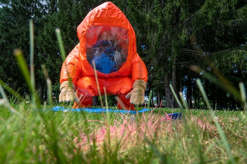 Image of person in a chemical suit collecting a sample.