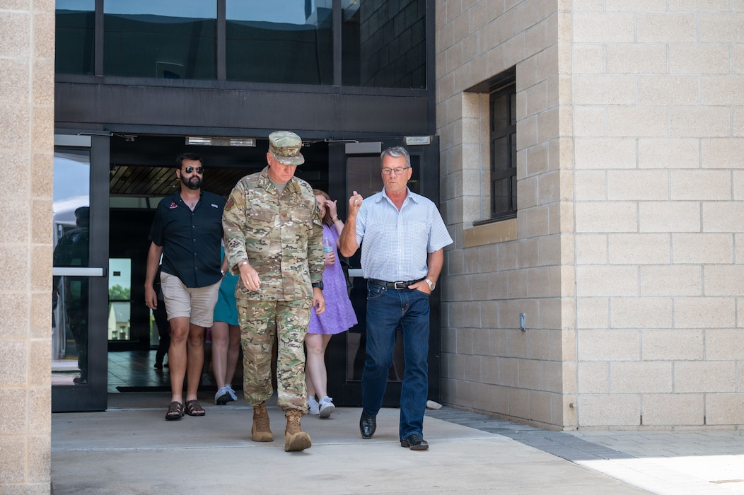 Two men lead a group of people walking out of a building