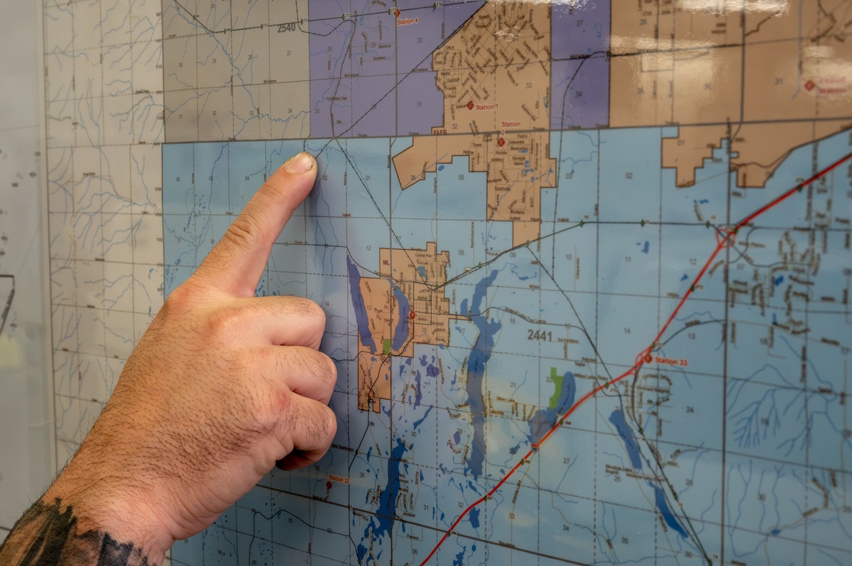 U.S. Air Force Master Sgt. Eric McNair, 92nd Operations Group first sergeant, points to a map of how close the brush fire came to Fairchild Air Force Base at Spokane County Fire District #3, Cheney, Washington, Aug. 5, 2026. Responding to emergencies as a volunteer firefighter helps protect the local community while demonstrating the commitment to service that supports military readiness. (U.S. Air Force photo by Airman Audie Curtis)