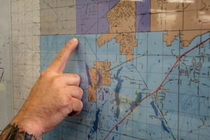 U.S. Air Force Master Sgt. Eric McNair, 92nd Operations Group first sergeant, points to a map of how close the brush fire came to Fairchild Air Force Base at Spokane County Fire District #3, Cheney, Washington, Aug. 5, 2026. Responding to emergencies as a volunteer firefighter helps protect the local community while demonstrating the commitment to service that supports military readiness. (U.S. Air Force photo by Airman Audie Curtis)