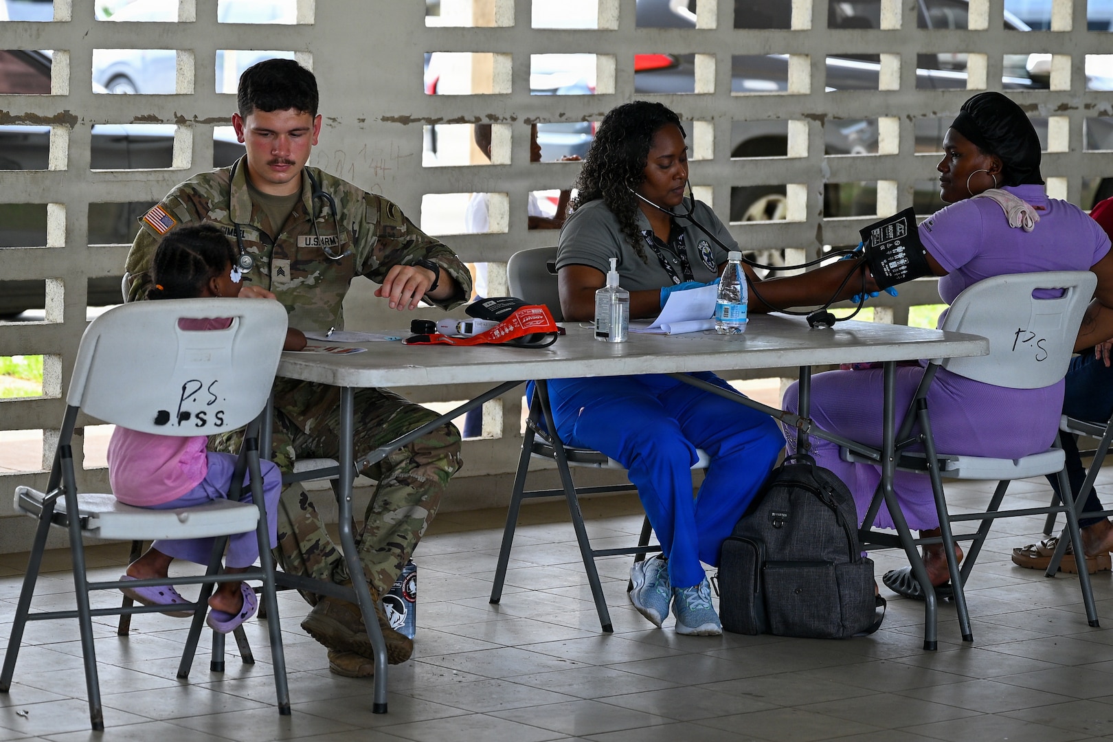 A U.S. Army Medic (left) works with a member of Panama's Ministerio de Salud (right) to take vitals of patients (far left and far right) during an exercise in Colon, Panama