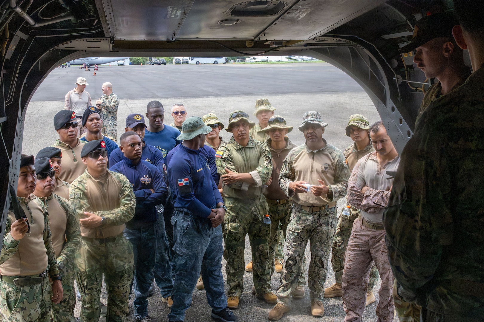 U.S. service members and members of partner nation military and security forces stand and listen at the entrance of a CH-47F Chinook as a U.S. service member speaks to the group from inside the Chinook.