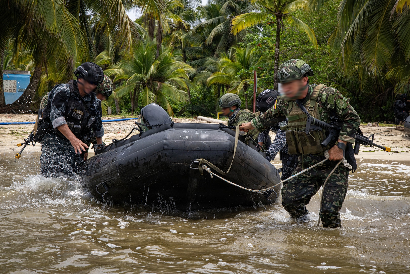 Members of Colombia's Military and the Policía Nacional de Panamá push a combat rubber raiding craft into the water