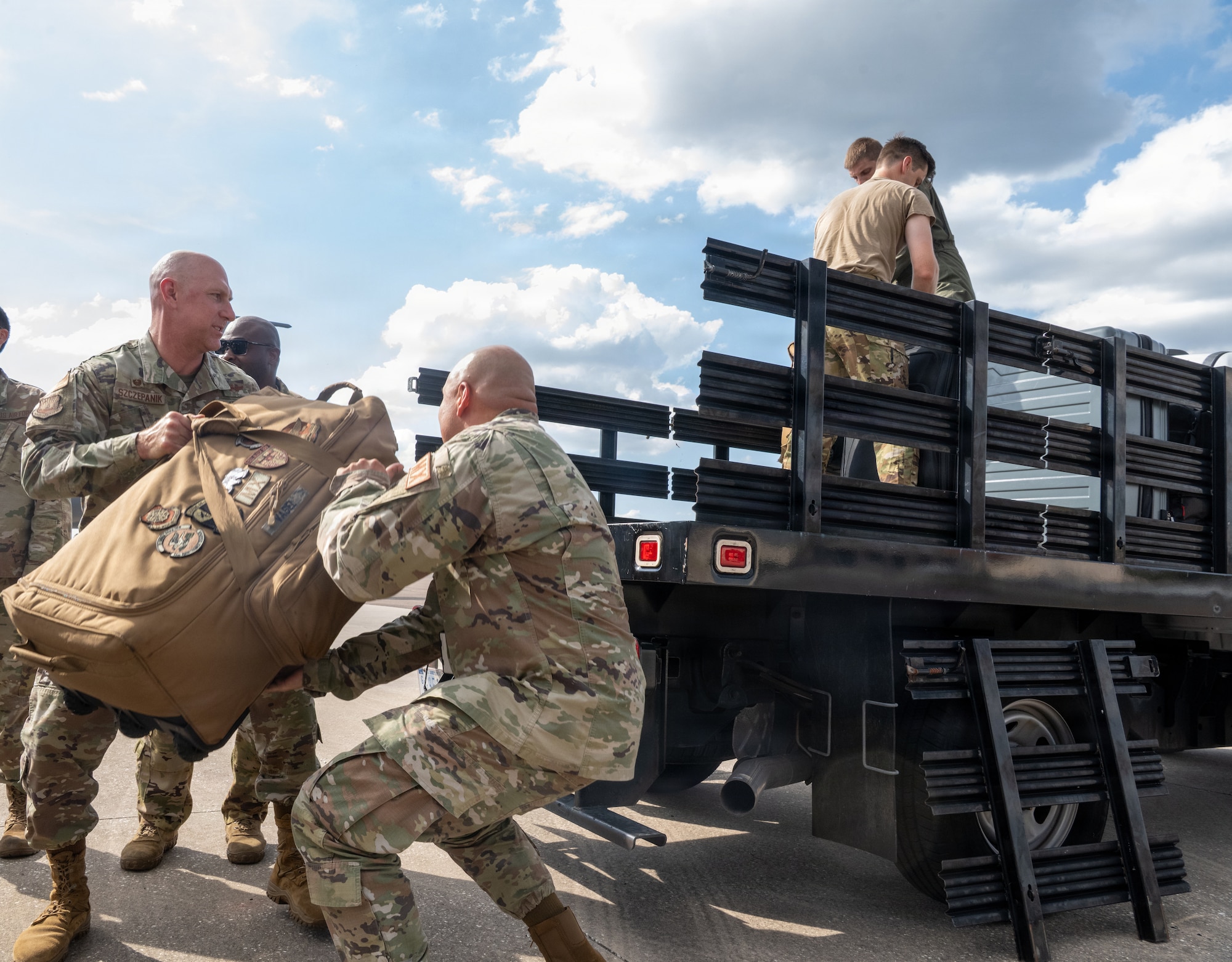 U.S. Air Force Col. Edward Szczepanik, 6th Air Refueling Wing commander, left, and Master Sgt. Alex Bautista, 6th Maintenance Group first sergeant, right, help load returning Airmen’s luggage during a redeployment at MacDill Air Force Base, Florida, July 2, 2026. Leadership assisted with the arrival process while welcoming Airmen home from deployment. (U.S. Air Force photo by Airman Micquill Davis)