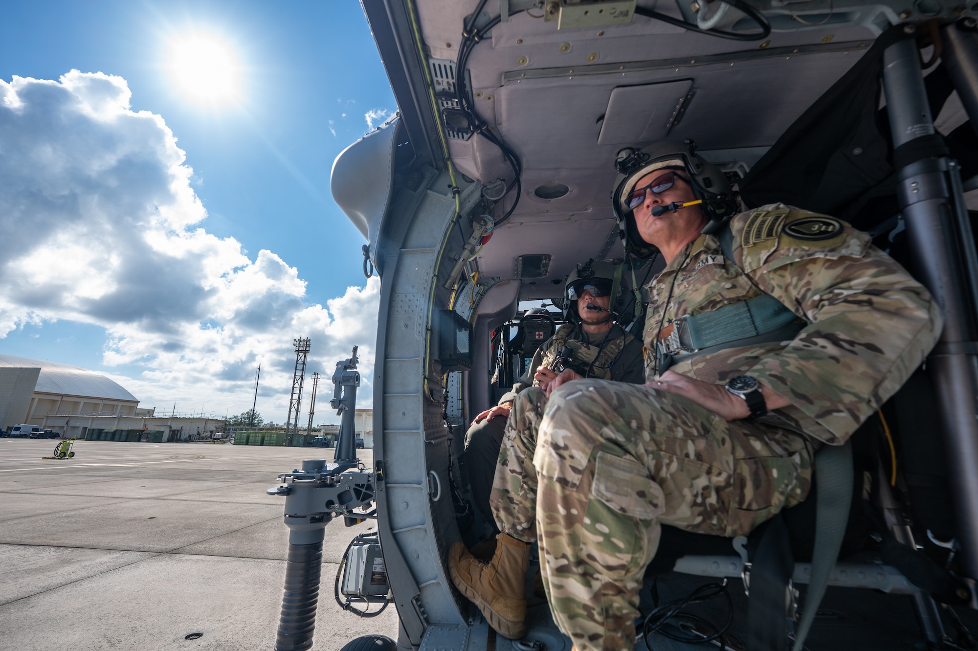 U.S. Air Force Brig. Gen. John Gallemore, left, 18th Wing commander, speaks with U.S. Army Lt. Gen. Steven Marks, vice commander of U.S. Special Operations Command and director of the Defense Autonomous Warfare Group, during an HH-60W Jolly Green Il flight over Kadena Air Base, Japan, July 23, 2026. Marks visited Kadena to engage with wing leadership, discuss DAWG initiatives and observe the installation's operational capabilities. (U.S. Air Force photo by Senior Airman Melany Bermudez)