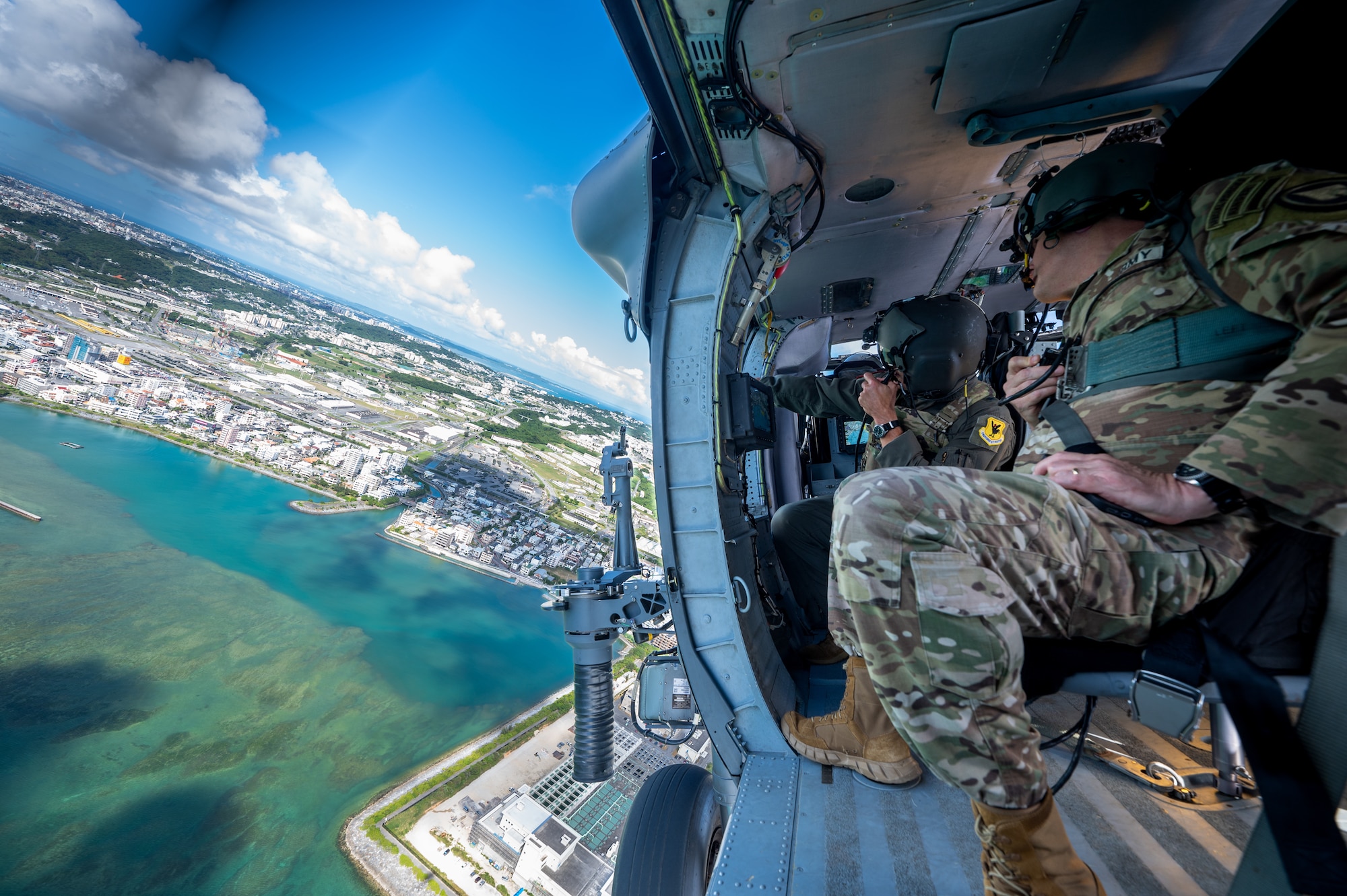 U.S. Air Force Brig. Gen. John Gallemore, left, 18th Wing commander, speaks with U.S. Army Lt. Gen. Steven Marks, vice commander of U.S. Special Operations Command and director of the Defense Autonomous Warfare Group, during an HH-60W Jolly Green Il flight over Kadena Air Base, Japan, July 23, 2026. The visit included a helicopter tour of the installation and a visit to the 18th Munitions Squadron to observe the wing's mission and capabilities. (U.S. Air Force photo by Senior Airman Melany Bermudez)