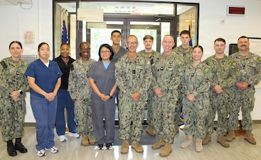 Rear Adm. Robert Hawkins, commander, Naval Medical Forces Atlantic (NMFL) and director of the Navy Nurse Corps, and Capt. Ken Radford, commanding officer, Navy Medicine Readiness and Training Command (NMRTC) Patuxent River, stand alongside active duty medical staff during a clinic tour at NMRTC-Detachment Indian Head, Aug. 4. Hawkins and Radford visited the command to engage directly with local clinic personnel, assess facilities, and discuss localized operational readiness.
