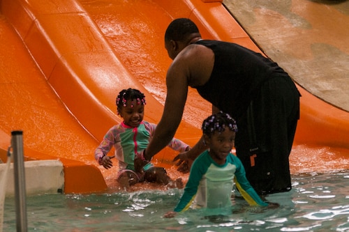 Father plays with children at waterpark.