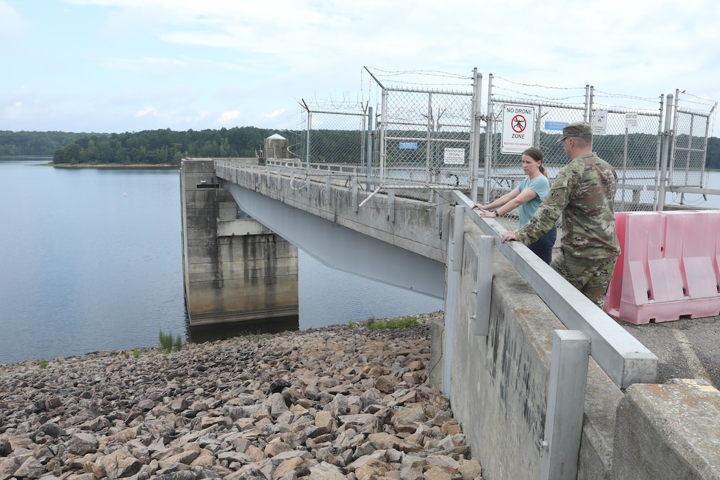 Two People standing on a dam , viewing Falls Lake
