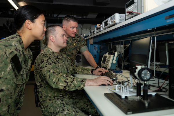 U.S. Navy Ensign Yvonne Fu, U.S. Navy Lt. Joshua McCowan and U.S. Marine Corps Lt. Col. Brian Neri, members of the Terahertz Imaging Camera team, review the technology’s concept of operations in the space systems lab at the Naval Postgraduate School (NPS) in Monterey, California, June 15, 2026. The Terahertz Imaging Camera is a low-cost, space-based terahertz imaging system for remote sensing of atomic oxygen emissions and other human-induced sources of terahertz radiation. (U.S. Navy photo by Mass Communication Specialist 2nd Class Abreen Padeken)