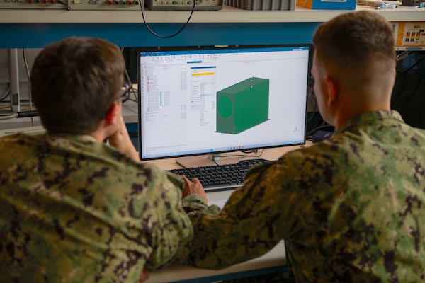 U.S. Navy Ensign Justin Williams and U.S. Navy Lt. Joshua McCowan demonstrate the Terahertz Imaging Camera system’s casing in the space systems lab at the Naval Postgraduate School (NPS) in Monterey, California, June 15, 2026. The Terahertz Imaging Camera was one of seven projects focused on key operational problems selected for funding through NPS’ inaugural Digital Trident AI Challenge in 2025, supported by the NPS Foundation and Alumni Association. (U.S. Navy photo by Mass Communication Specialist 2nd Class Abreen Padeken)
