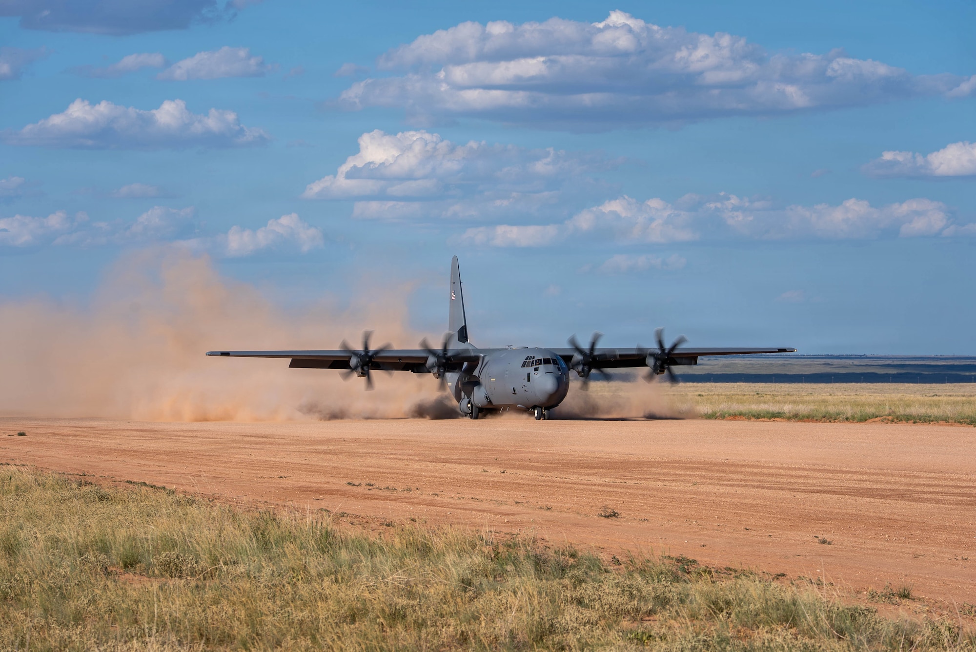 Airmen help a C-130J Super Hercules land on a dirt strip runway