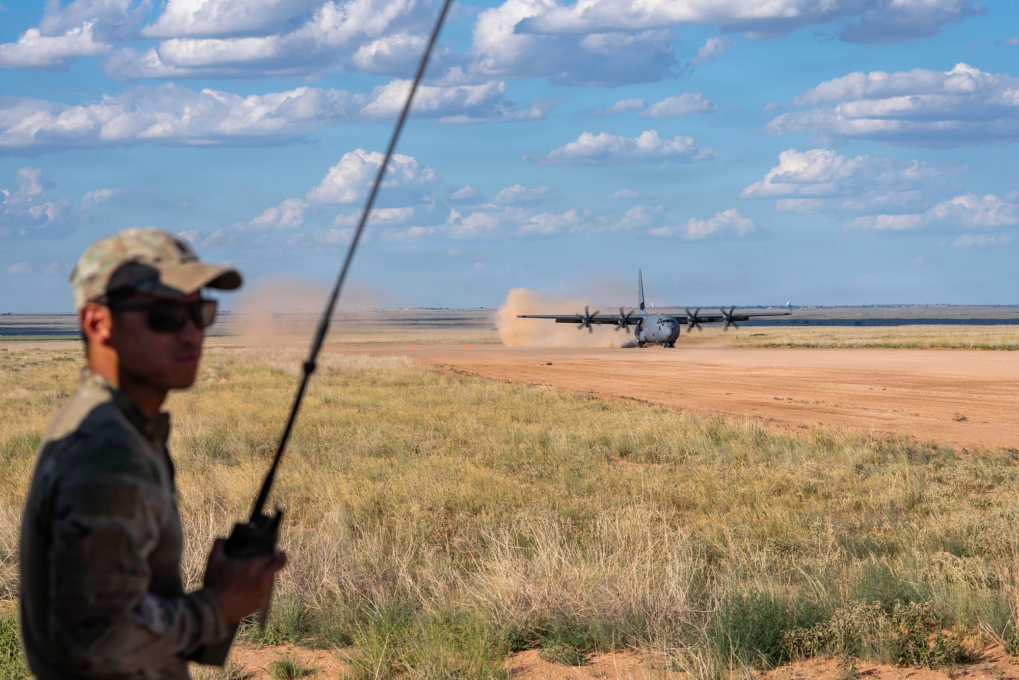 Airmen help a C-130J Super Hercules land on a dirt strip runway