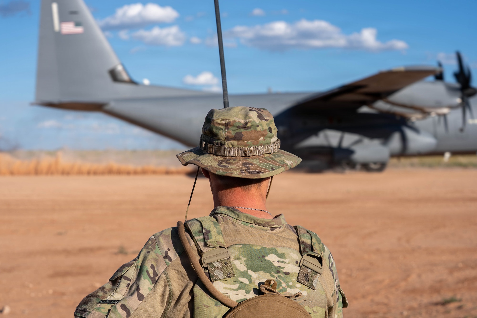 Airmen help a C-130J Super Hercules land on a dirt strip runway