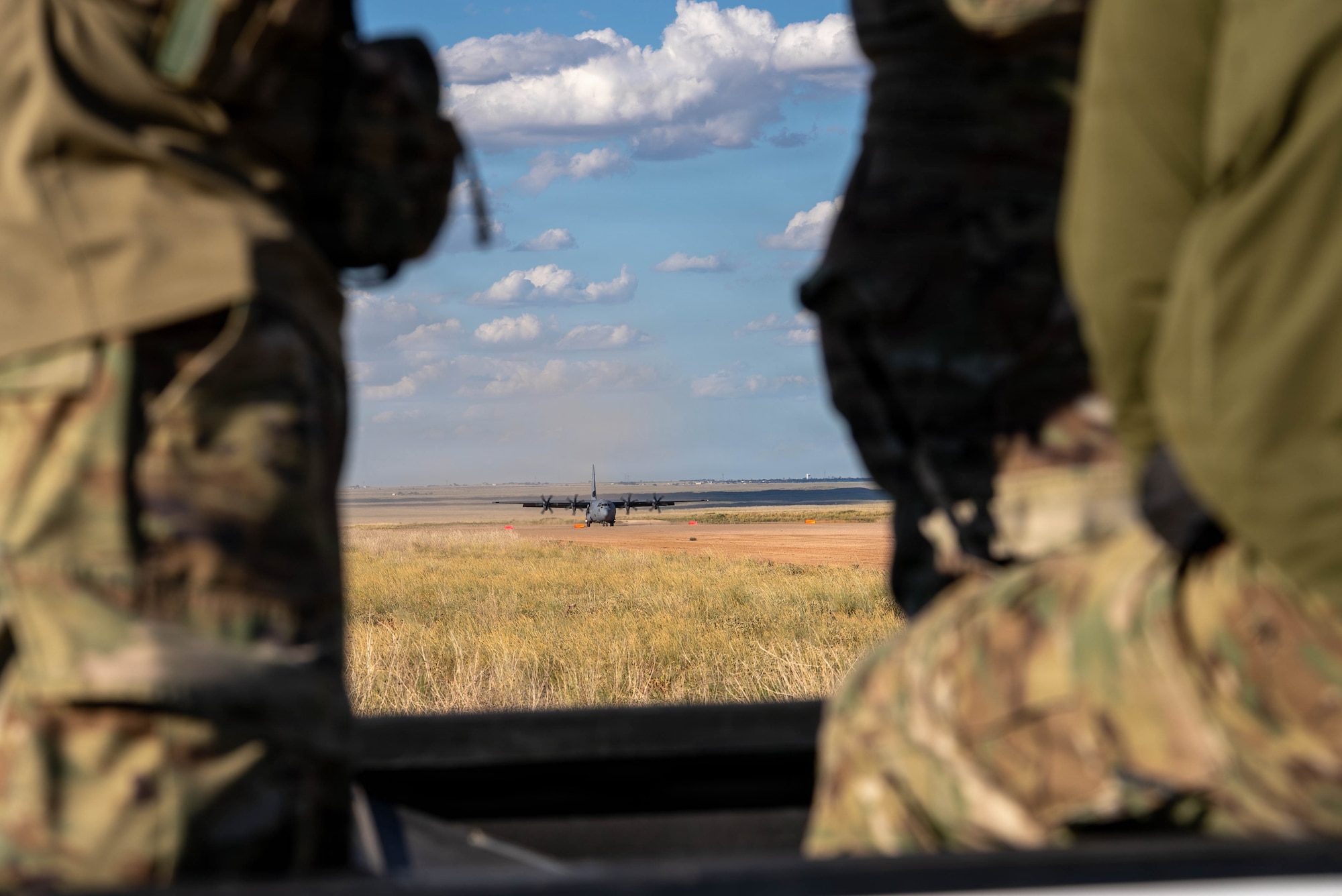 Airmen help a C-130J Super Hercules land on a dirt strip runway