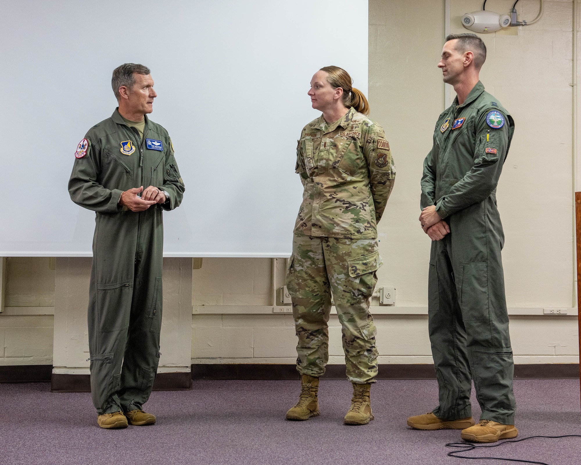 U.S. Air Force Capt. Zach Siefken, right, 961st Airborne Air Control Squadron E-3 Century pilot and 2nd Lt. Holly Siefken, middle, 18th Medical Group officer in charge of quality assurance, at Kadena Air Base, Japan, July. 23, 2026. The coin recognized their role in a lifesaving response, during which they assisted neighbors in administering CPR, applying an automated external defibrillator and guiding emergency responders to the scene. (U.S. Air Force photo by Naoto Anazawa)