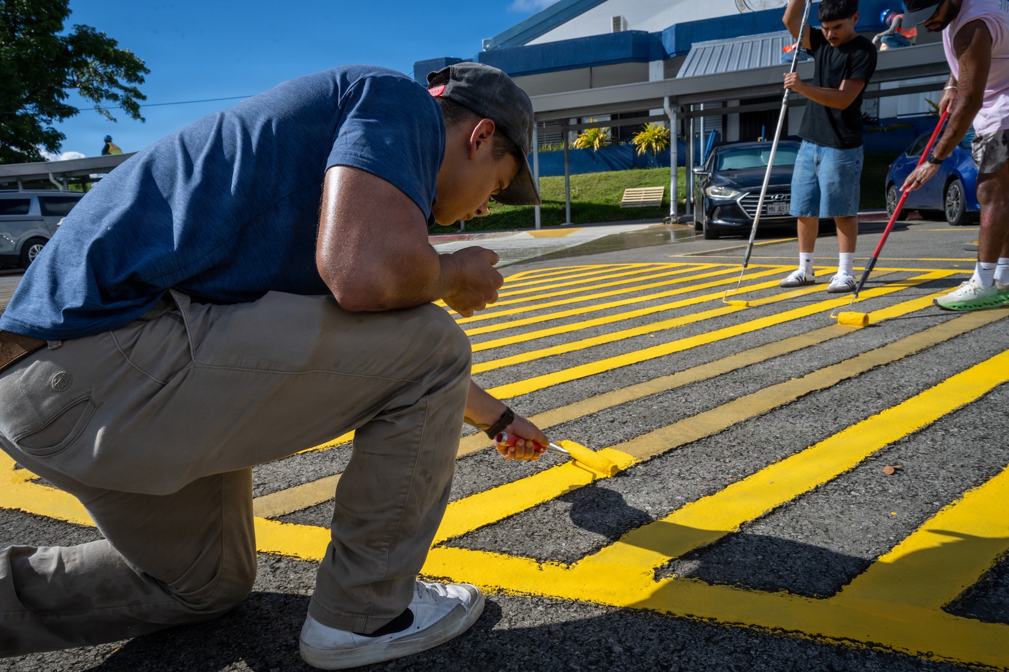 U.S. Air Force Senior Airman Brandon Ramirez, 21st Combat Air Base Squadron explosive ordinance disposal technician, repaints parking lot markings at Chalan Pago-Ordot Elementary School, Guam, June 12, 2026. Airmen assigned to the 21st Air Task Force worked alongside local educators and community members to restore school facilities damaged by Super Typhoon Sinlaku and Super Typhoon Bavi. (U.S. Air Force photo by Senior Airman Adrien Tran)
