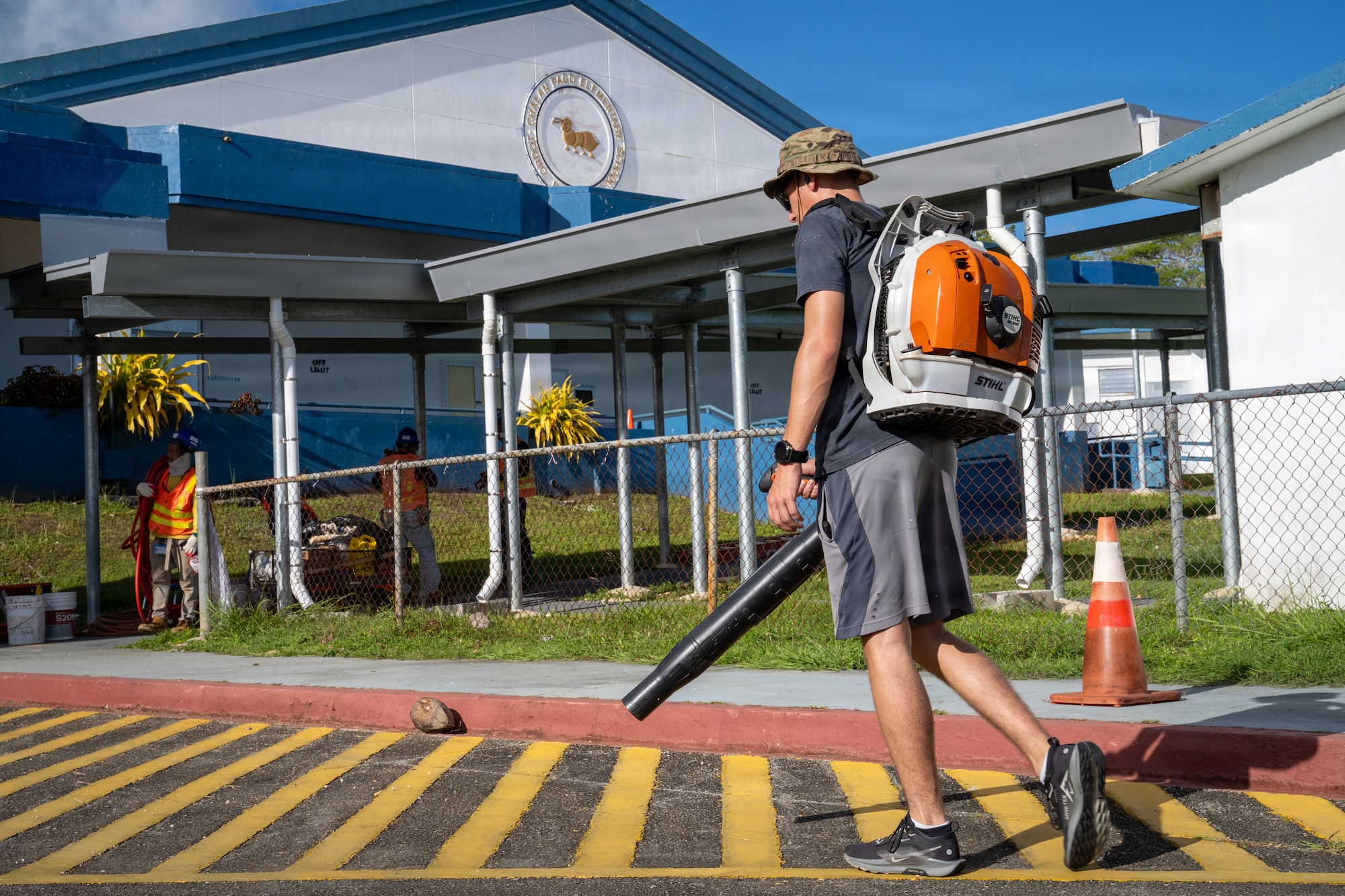 U.S. Air Force Senior Airman Michael Capehart, 21st Combat Air Base Squadron airfield manager, clears debris at Chalan Pago-Ordot Elementary School, Guam, June 12, 2026. Airmen assigned to the 21st Air Task Force volunteered at schools across Guam to remove storm debris, repaint parking lot markings and help prepare campuses for the upcoming school year following Super Typhoon Sinlaku and Super Typhoon Bavi. (U.S. Air Force photo by Senior Airman Adrien Tran)