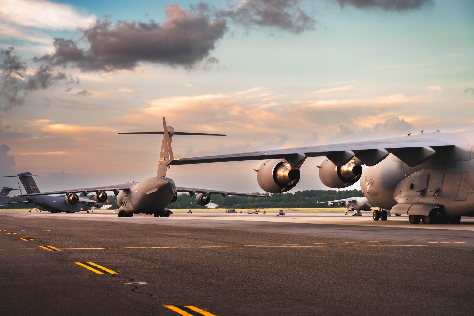 A photo of four C-17 Globemaster III driving across the flightline.