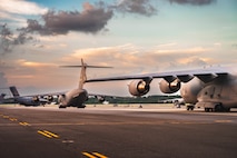 A photo of four C-17 Globemaster III driving across the flightline.