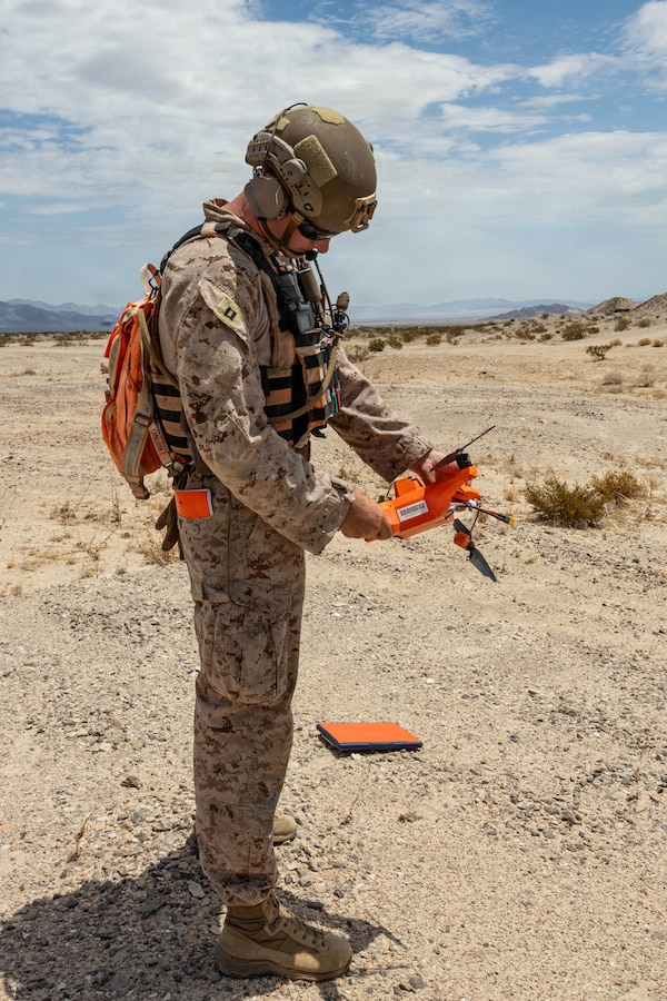 U.S. Marine Corps Capt. Joseph Smith, a Nebraska native and low altitude air defense officer with Tactical Training and Exercise Control Group, Marine Corps Air Ground Combat Center, inspects a neutralized simulated enemy Unmanned Aerial System during Counter-small Unmanned Aerial System training as part of Service Level Training Exercise 4-26 at Training Area Prospect, Marine Corps Air Ground Combat Center, Twentynine Palms, California, July 17, 2026. With the debut of C-sUAS lanes at the Combat Center, Marines recognize and respond to unmanned aerial threats by employing emerging tactics, techniques, procedures, and maintaining a C-sUAS mindset in every operation, all while preserving the fundamentals that make rifle squads survivable and lethal. SLTE is a premier training event that ensures the Marine Corps remains a highly lethal, adaptable force capable of dominating the future multi-domain fight. (U.S. Marine Corps photo by Lance Cpl. Cody Fitzgerald)
