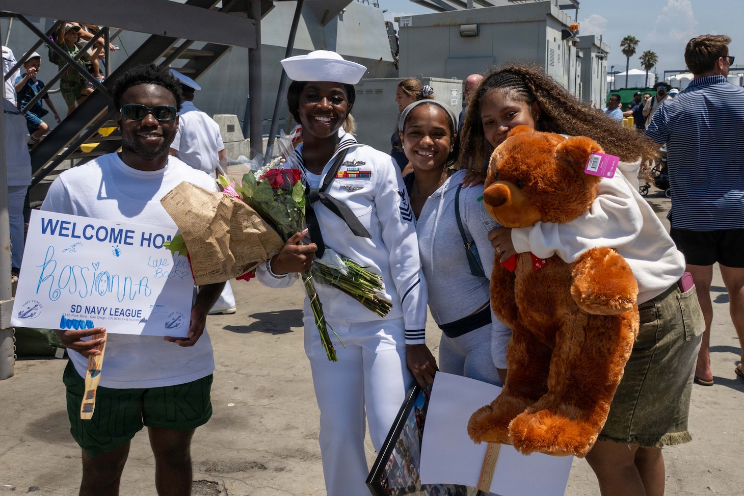 U.S. Navy Sailors in dress whites pose on a pier at the homecoming of USS Pinckney (DDG 91).