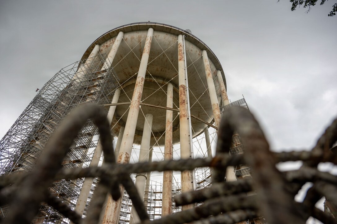 A water tower has scaffolding built on the left side of it.