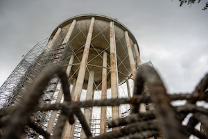 A water tower has scaffolding built on the left side of it.