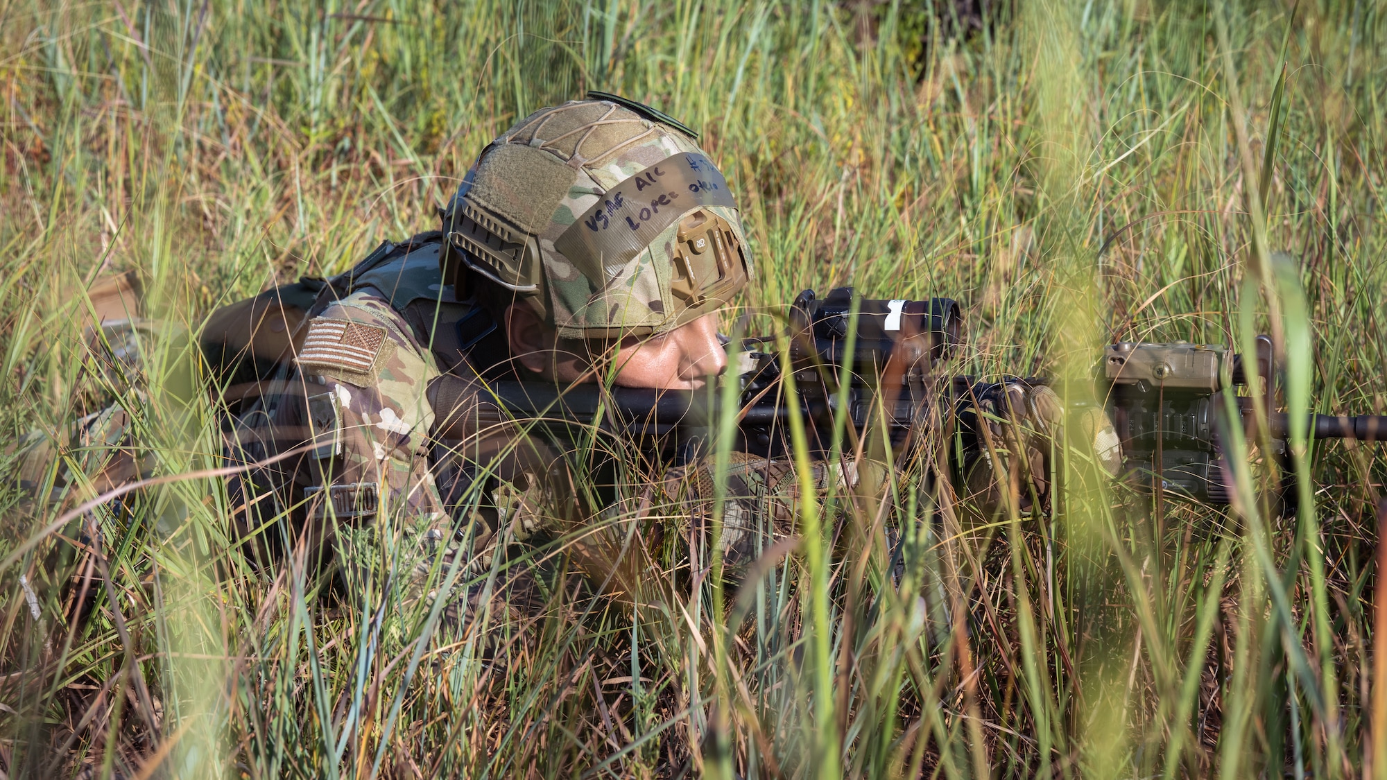 Airman pointing gun in the tall grass