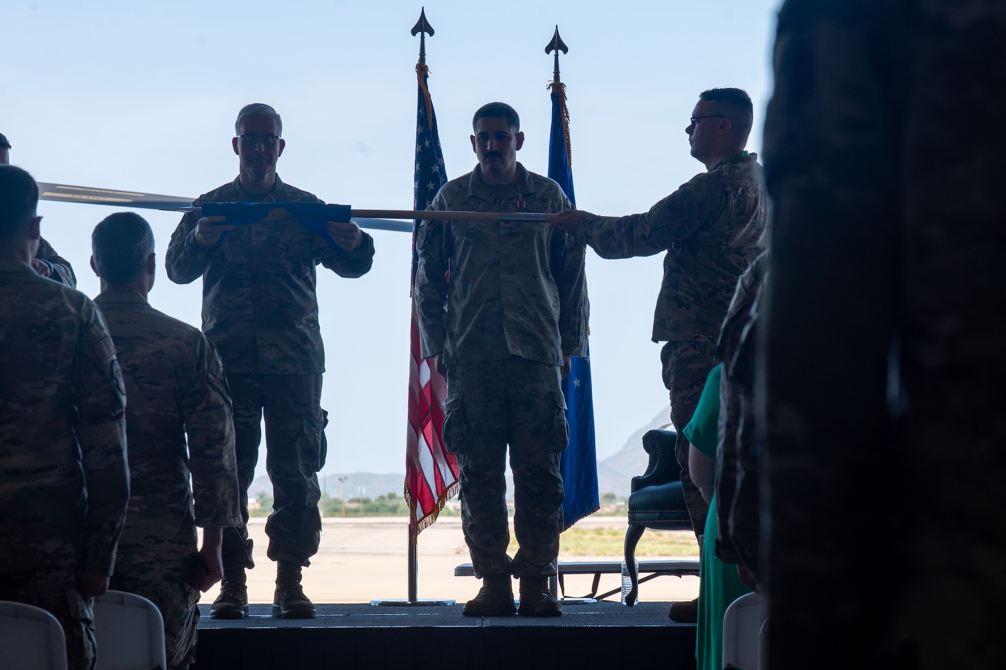 U.S. Air Force Col. Duane Denney, 355th Maintenance Group commander, left, and Maj. Daniel Incorvaia, 55th Rescue Generation Squadron commander,  roll up a guidon during the 55th RGS inactivation ceremony at Davis-Monthan Air Force Base, Arizona, Aug. 10, 2026. The squadron’s guidon was furled and cased, marking the end of the unit’s service. (U.S. Air Force photo by Airman 1st Class Jaden Kidd)