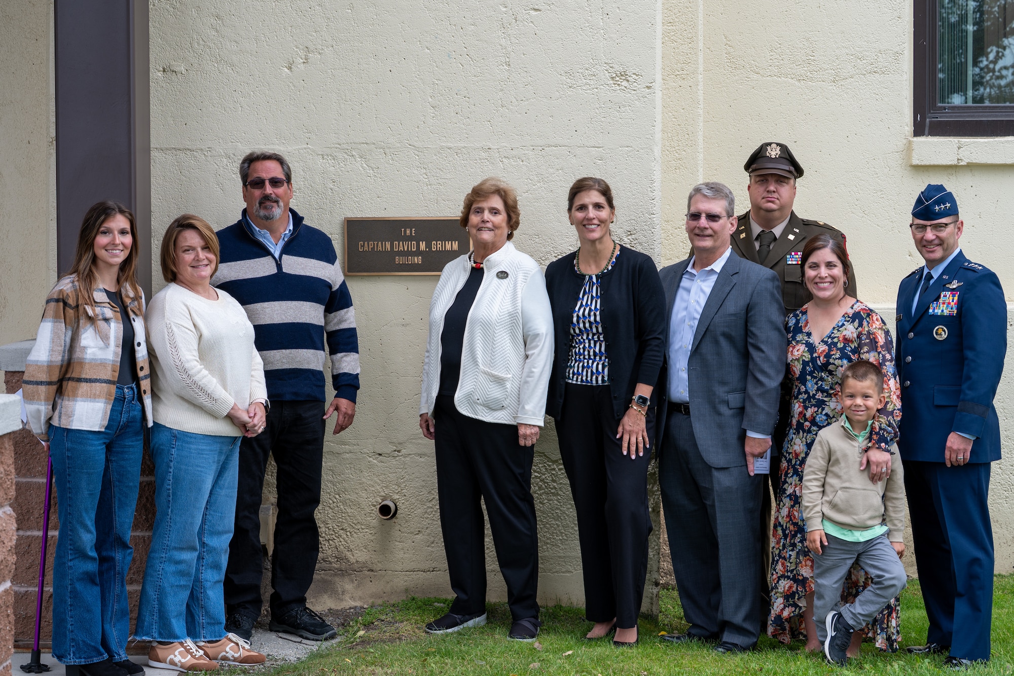 Dana Grimm, wife of the late Capt. David M. Grimm, poses with family members and U.S. Air Force Lt. Gen. Robert Davis, commander, Alaskan Command, Alaska North American Aerospace Defense Command Region, and Eleventh Air Force, in front of the newly dedicated Capt. David M. Grimm Building sign at Joint Base Elmendorf-Richardson, Alaska, Aug. 7, 2026.