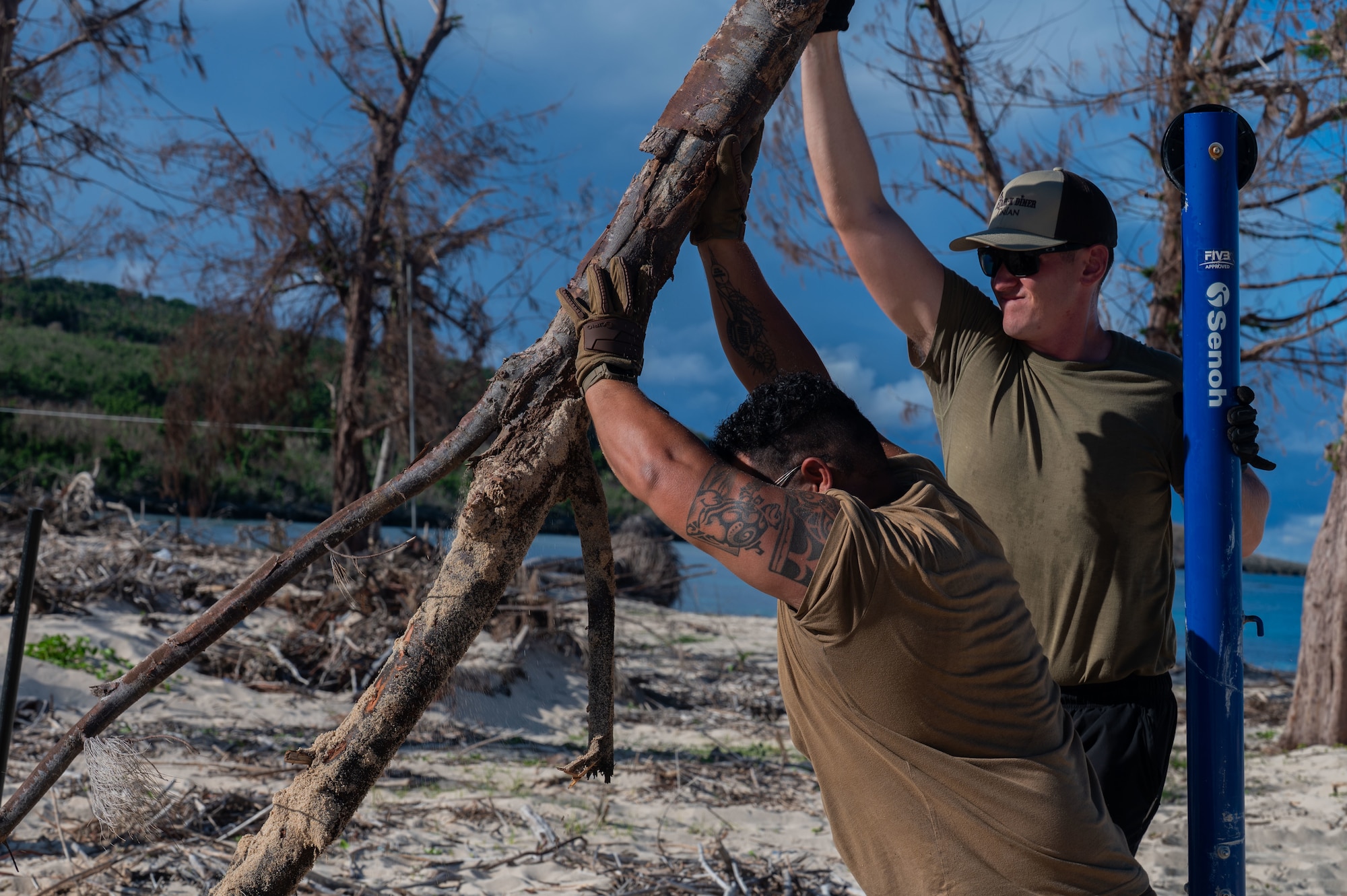 U.S. Air Force Senior Airman Brandon Sanislo, 21st Combat Air Base Squadron structural apprentice, right, and Staff Sgt. Emmanuel Medina, 21st CABS electrical systems specialist, clear fallen trees and debris during disaster recovery operations on Tinian, Commonwealth of the Northern Mariana Islands, June 9, 2026. The 21st CABS deployed as a cohesive Unit of Action, leveraging multi-skilled, Mission-Ready Airmen to conduct rapid debris clearance and restore critical public spaces in support of the Federal Emergency Management Agency. All Department of War disaster response efforts are executed in close coordination with local and territorial civil officials to ensure an efficient, unified recovery. (U.S. Air Force photo by Senior Airman Alondra Cristobal)