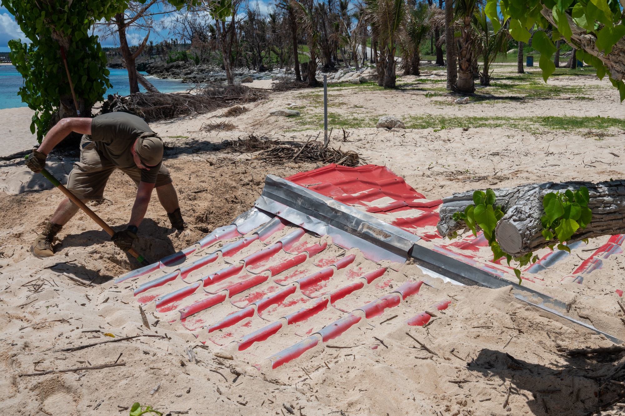 U.S. Air Force Senior Airman Milan Herbold, 21st Combat Air Base Squadron water and fuel systems maintenance journeyman, clears storm-damaged roofing material on Tinian, Commonwealth of the Northern Mariana Islands, June 10, 2026. The 21st CABS focused on restoring essential public spaces, establishing temporary shelters and improving conditions for local communities after Typhoon Sinlaku caused sever infrastructure damage. The Department of War works in close coordination with the Federal Emergency Management Agency and territorial civil officials to deliver a unified and efficient disaster response. (U.S. Air Force photo by Senior Airman Alondra Cristobal)