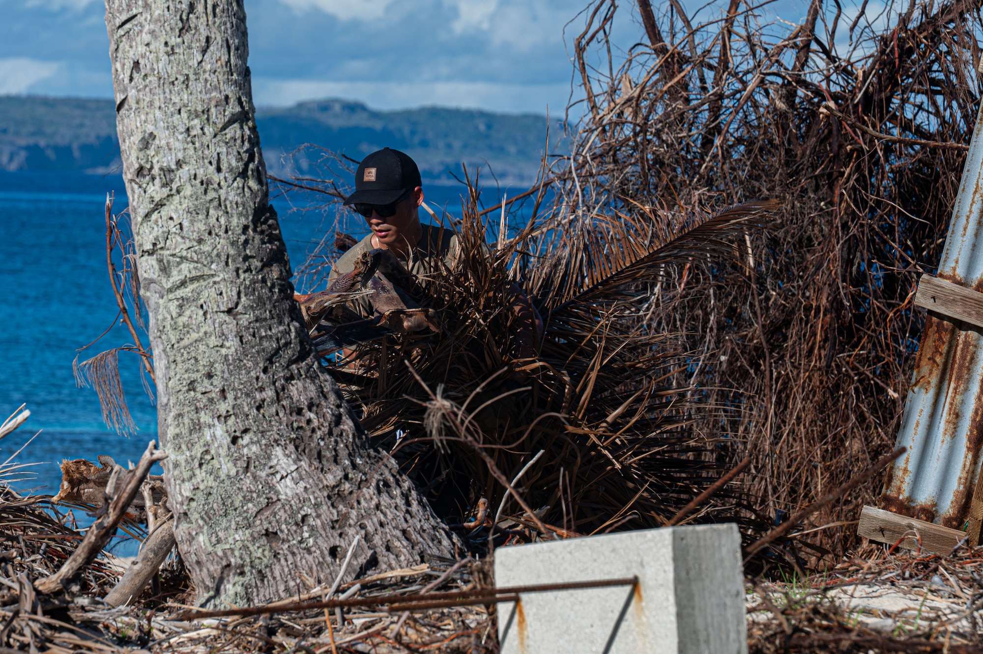 U.S. Air Force Senior Airman Justin Nieves, 21st Combat Air Base Squadron heating, ventilation and air conditioning apprentice, clears structural debris on Tinian, Commonwealth of the Northern Mariana Islands, June 9, 2026. The 21st CABS utilized cross-functional, Mission-Ready Airmen to accelerate recovery efforts following Typhoon Sinlaku. (U.S. Air Force photo by Senior Airman Alondra Cristobal)