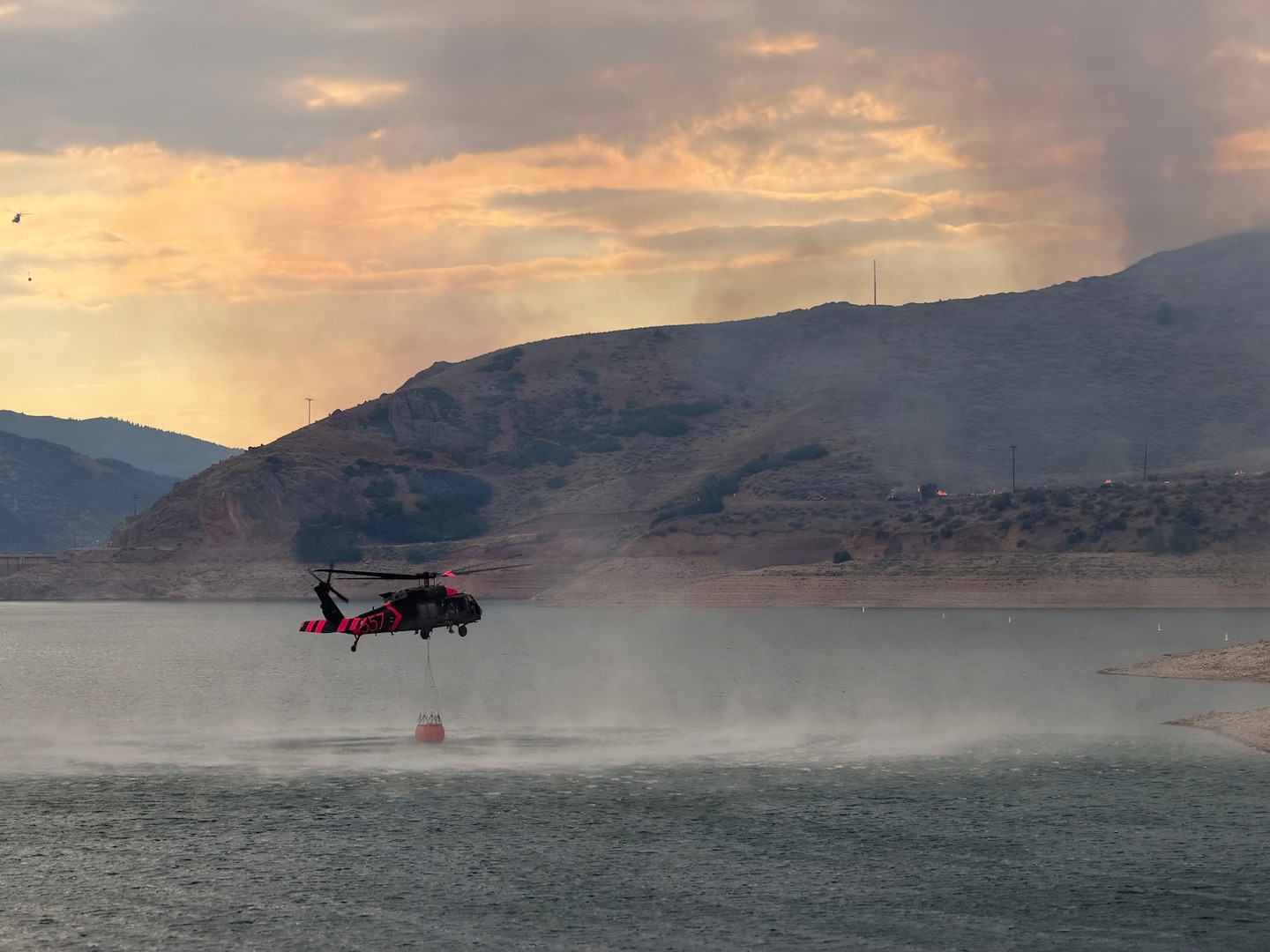 A Utah National Guard UH-60 Black Hawk collects water in a bucket from East Canyon Reservoir while aerial firefighting operations in support of the Rocky Canyon Fire in Morgan County, Utah, Aug. 9, 2026.