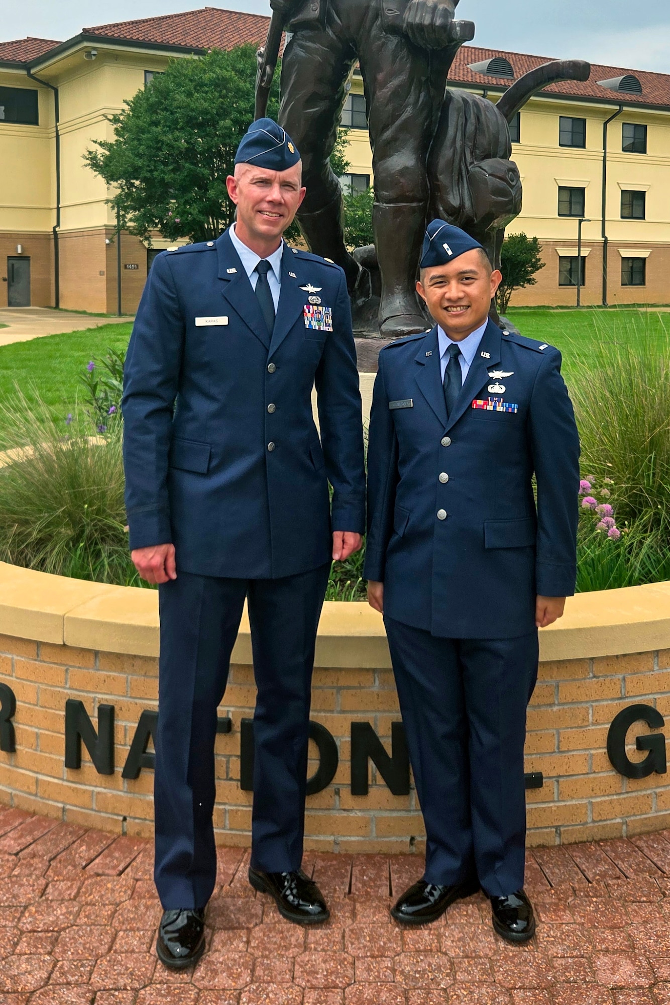 Airmen posing for photo in front of statue.