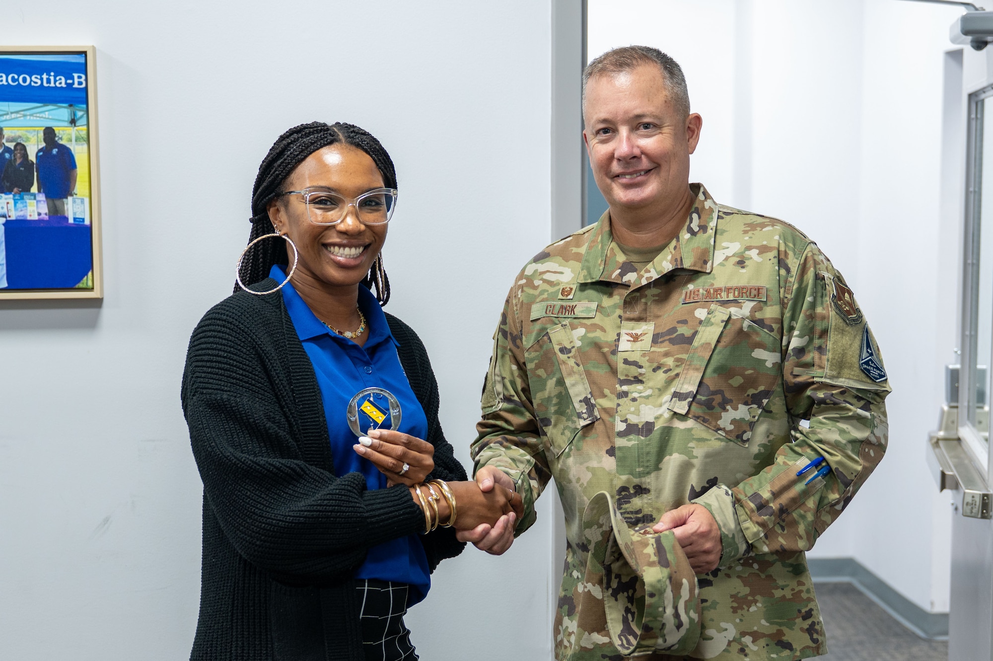 Tamara Mason, left, 11th Force Support Squadron Relocation Program Manager, receives a challenge coin from U.S. Air Force Col. James M. Clark, commander of the 11th Wing and Joint Base Anacostia-Bolling.
