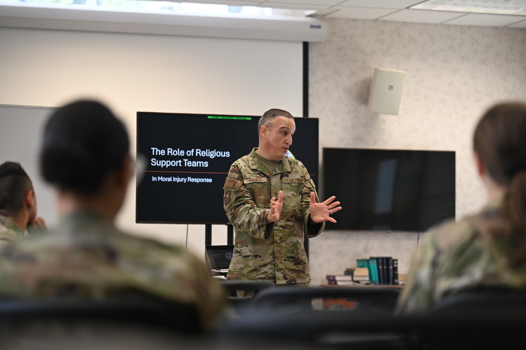 Man in uniform stands in front of a class and speaks.