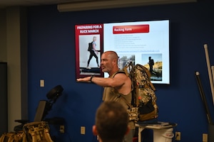 Man speaks to class with PowerPoint in background.