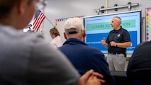 A photo of a man instructing a classroom of people.